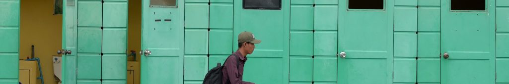 This photo taken on November 7, 2017 shows a Cambodian man walking past public toilets on a street in Phnom Penh. / AFP PHOTO / TANG CHHIN SOTHY